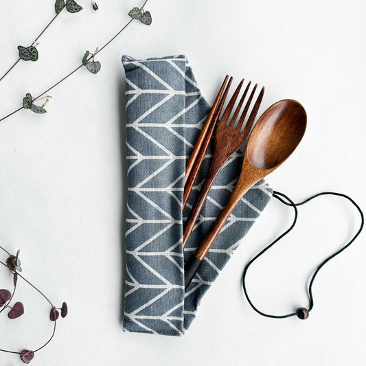 Reusable natural wood cutlery set with spoon, fork, chopsticks, and patterned cloth pouch.