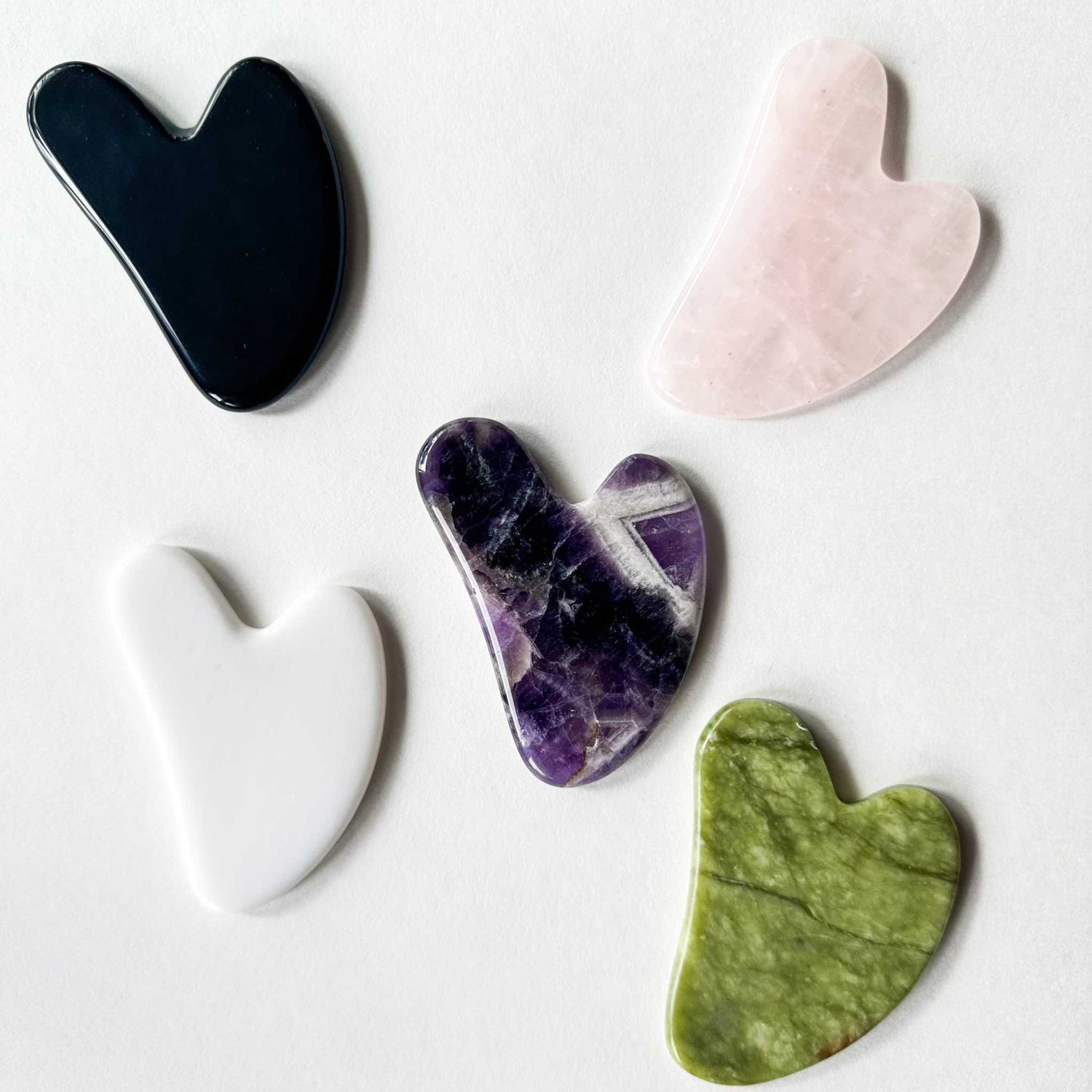 Set of six natural gua sha stones including rose quartz, jade, amethyst, obsidian, white jade, and opalite for facial and body massage